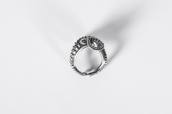 Close-up of a handcrafted silver ring with intricate details on a soft fabric background