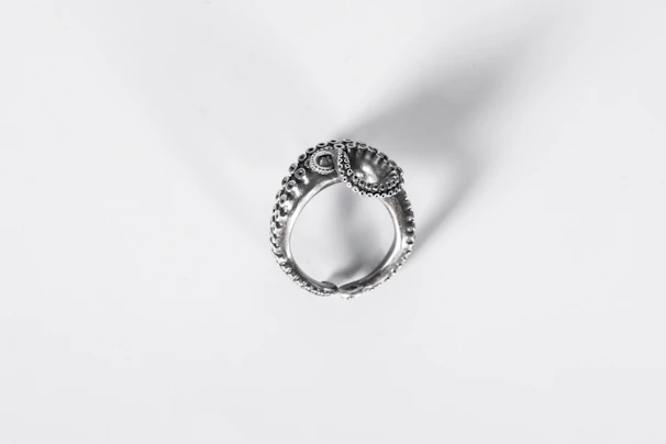Close-up of a delicate handcrafted silver filigree ring glowing softly under warm light