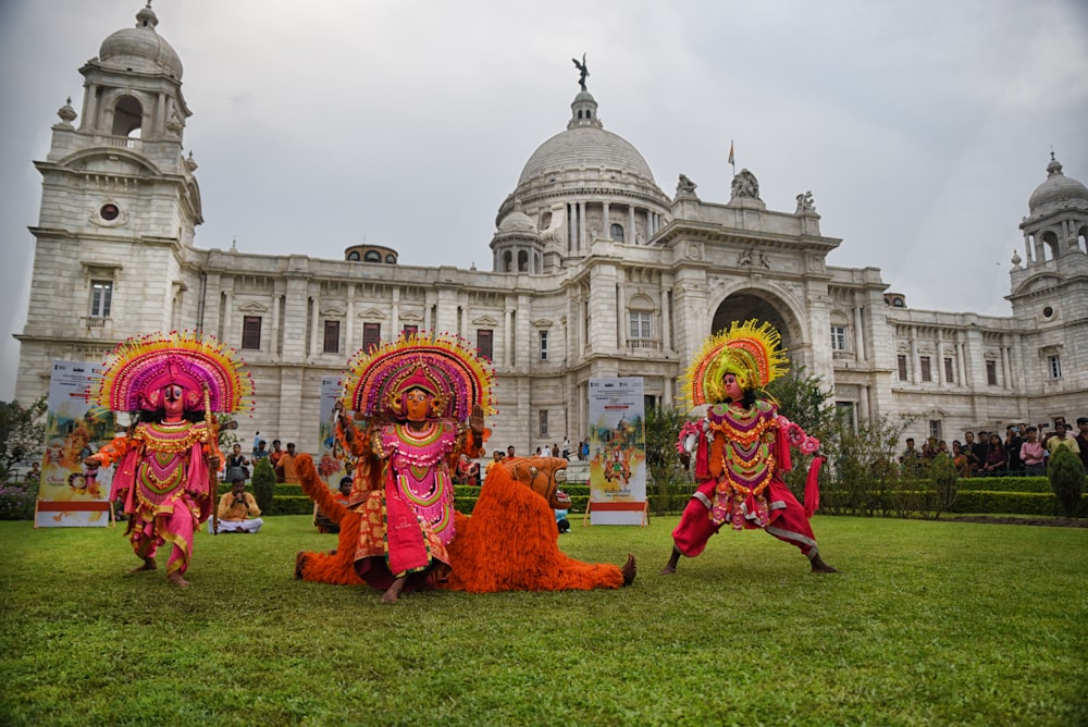 a group of people in clothing in front of a large building