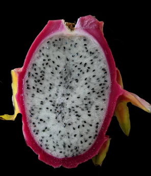 Close-up of vibrant white dragon fruit sliced open, showcasing its speckled interior.