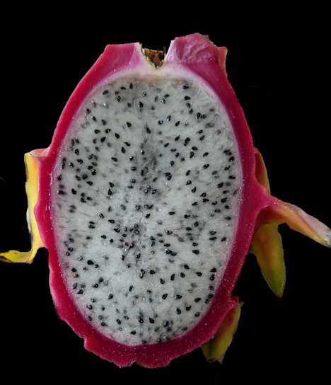 Close-up of vibrant white dragon fruit sliced open, showcasing its speckled interior.