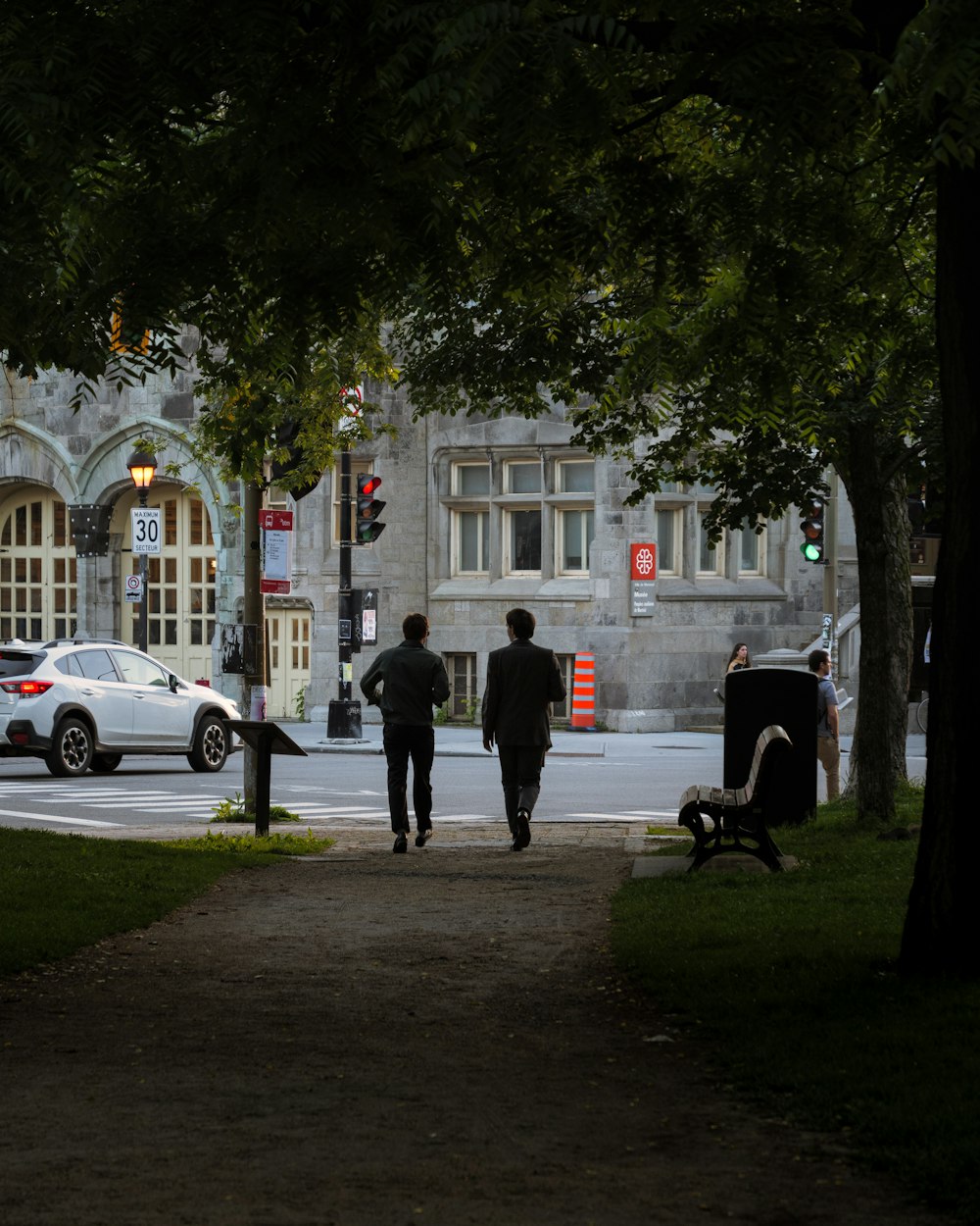 a couple of men walking down a sidewalk next to a building