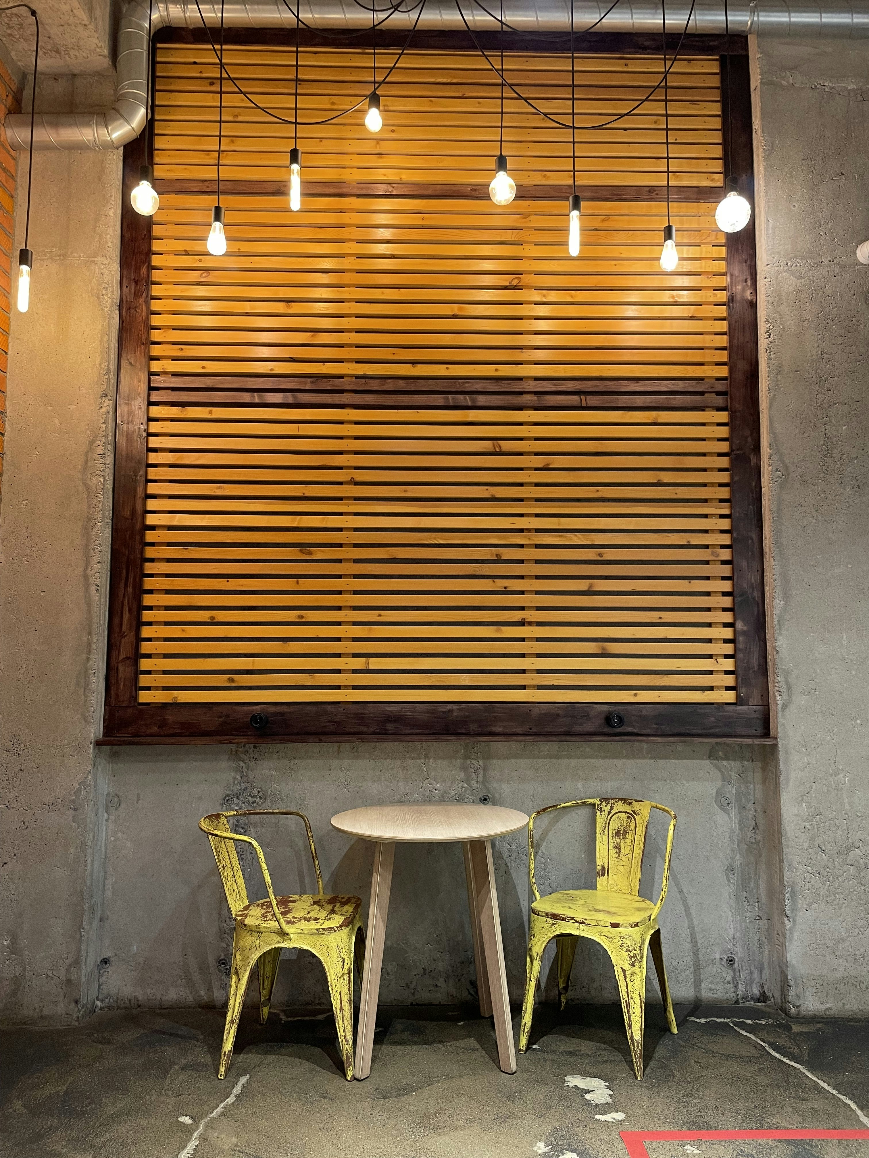 una mesa y sillas frente a una pared de madera con luces