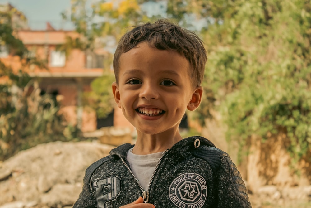 a boy smiling with a bird on his shoulder