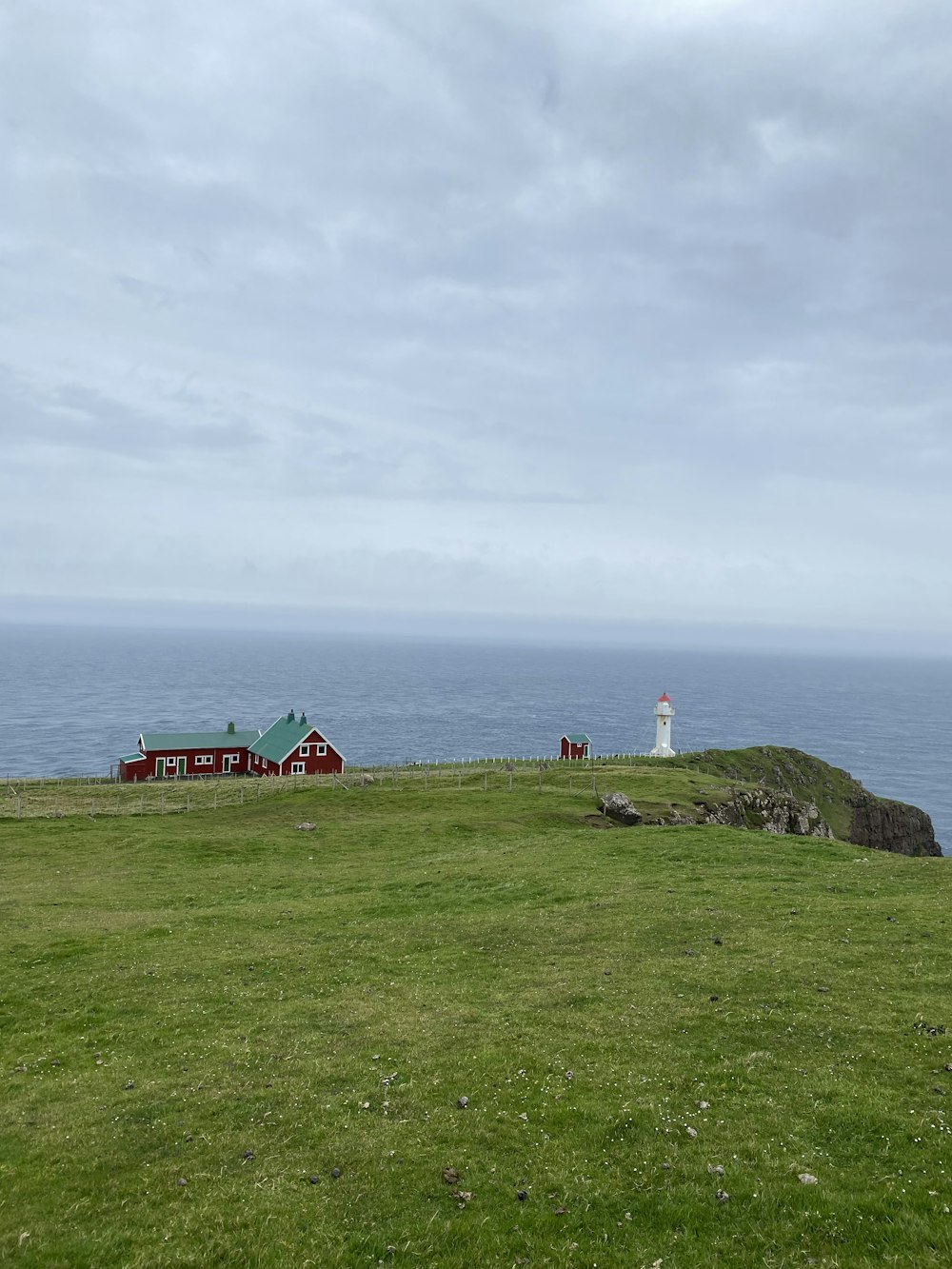 a lighthouse on a grassy hill by the water