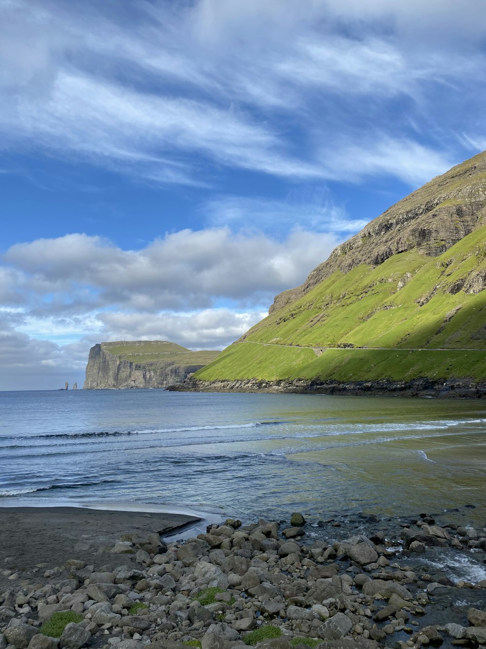 a rocky beach with a hill in the background