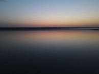 A serene watercolor of a calm lake reflecting a pastel sunset sky.