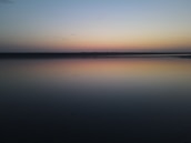 Peaceful sunset over a quiet lake reflecting soft pastel colors.