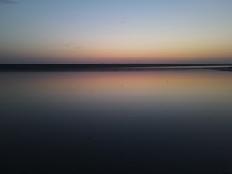 Peaceful sunset over a quiet lake reflecting soft pastel colors.