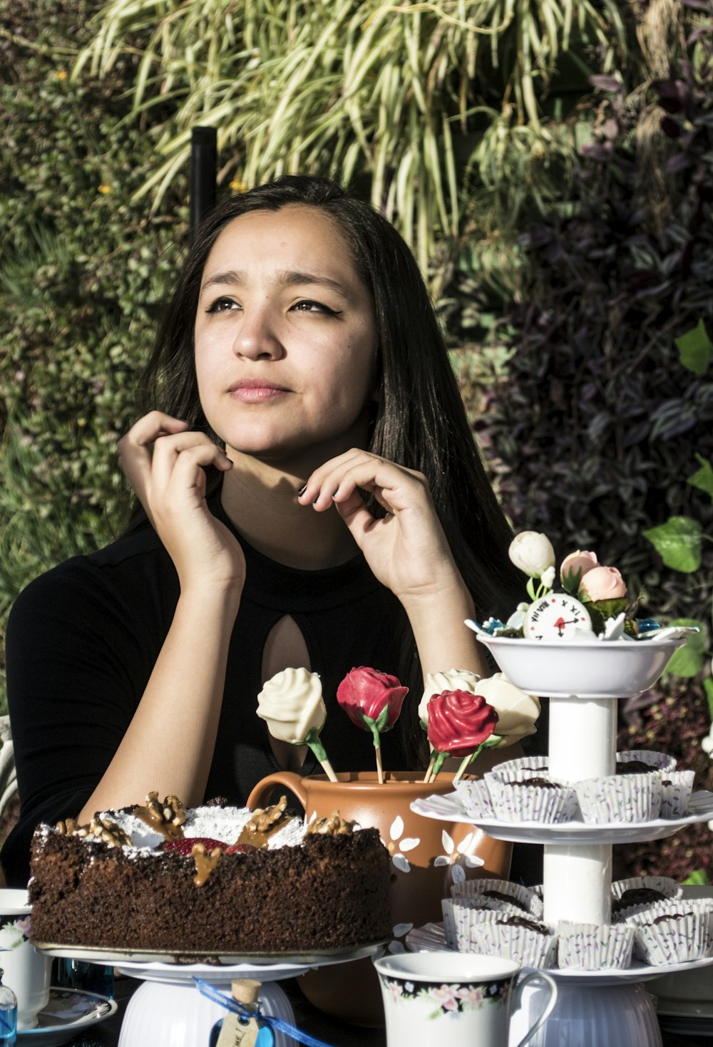 a woman sitting at a table with a cake and flowers