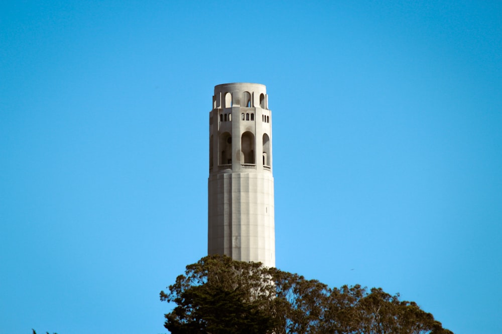 a tall white tower with Coit Tower in the background