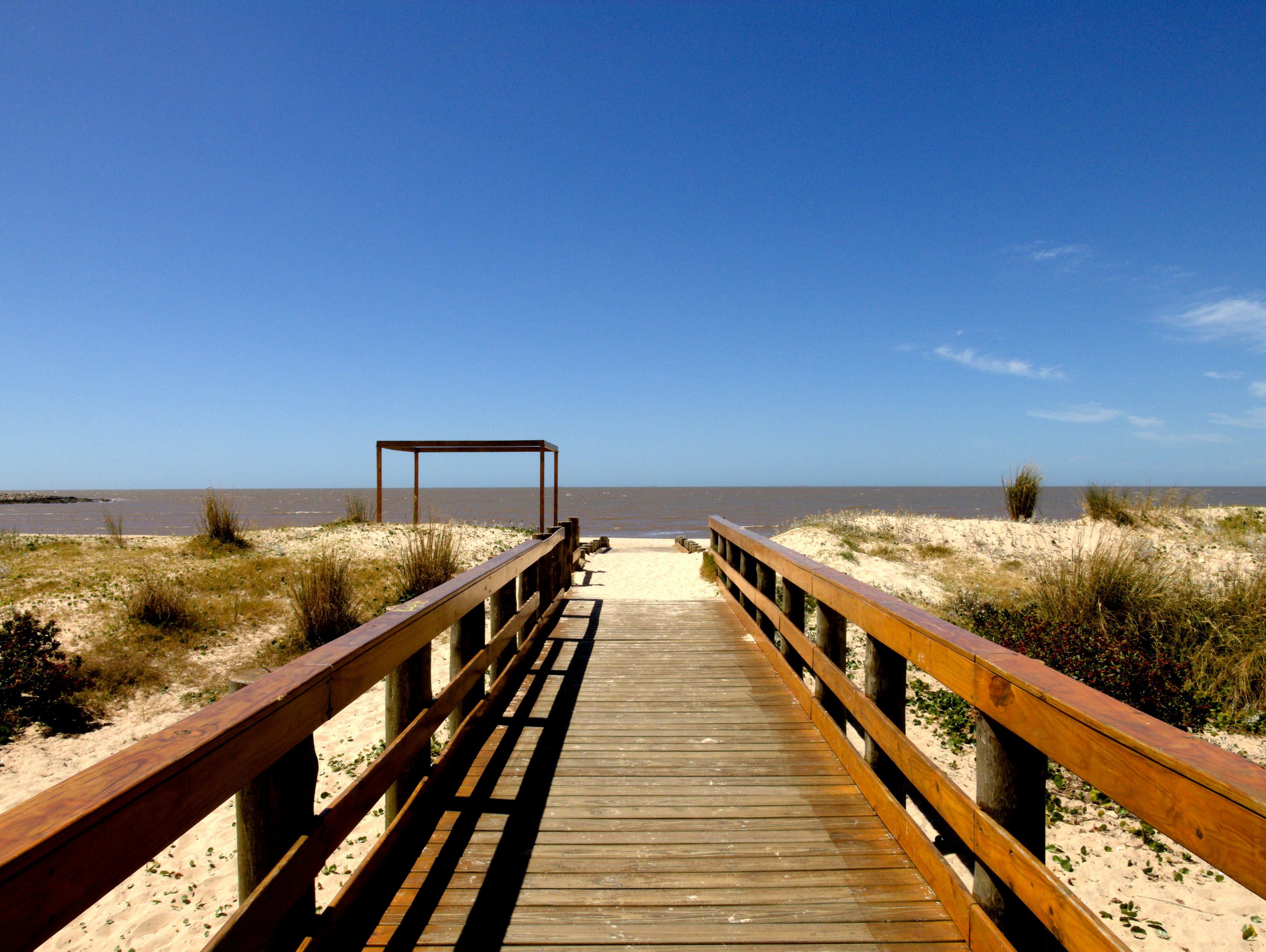 a wooden bridge over a beach, 