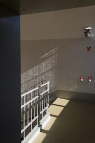 a white tiled room with a metal railing and a white railing