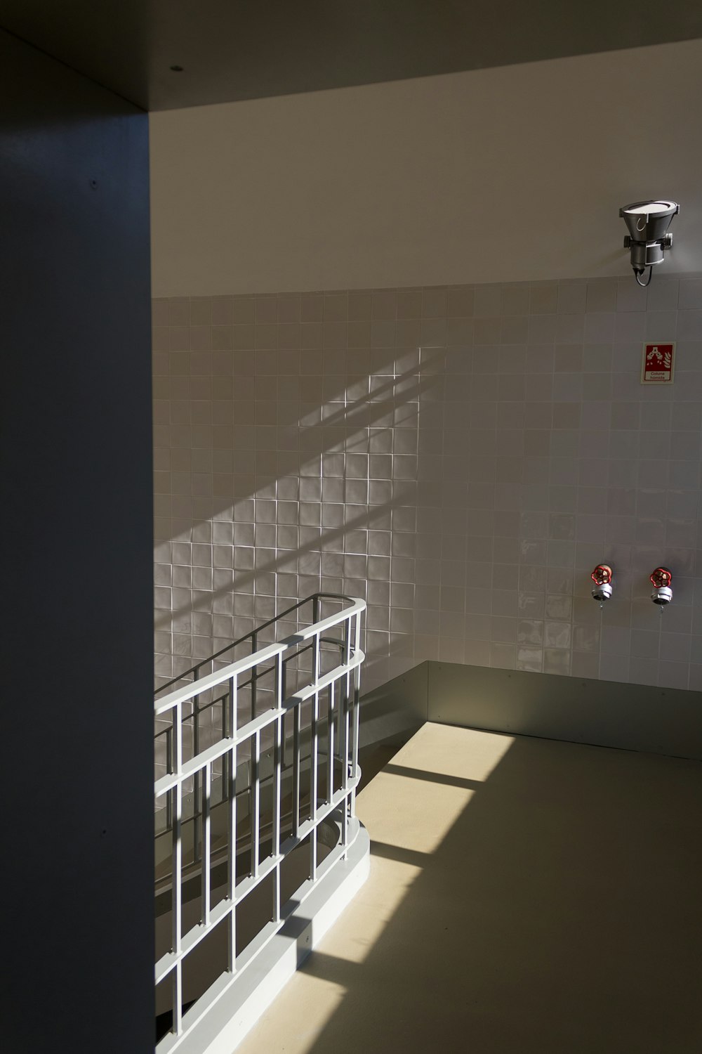 a white tiled room with a metal railing and a white railing