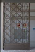 Custom steel gate with intricate geometric patterns at a commercial building entrance.