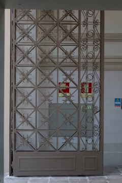 A sleek black metal gate with intricate geometric patterns at a modern home entrance.