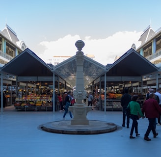 a group of people walking around a courtyard with a fountain in it