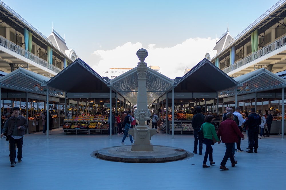 a group of people walking around a courtyard with a fountain in it