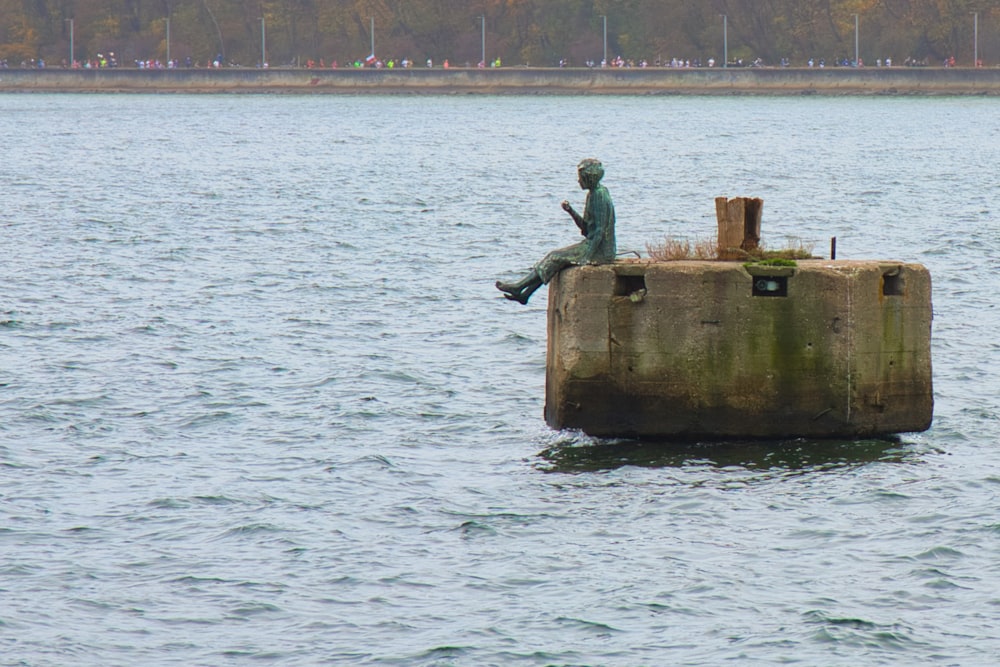 a statue on a platform in the middle of a body of water