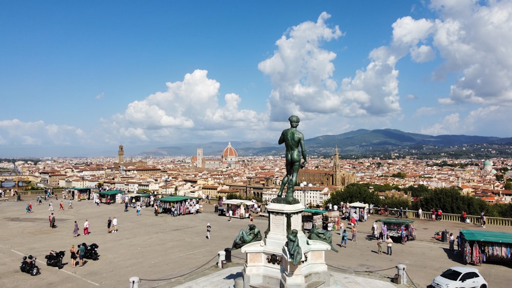 a statue in a plaza with people and buildings in the background