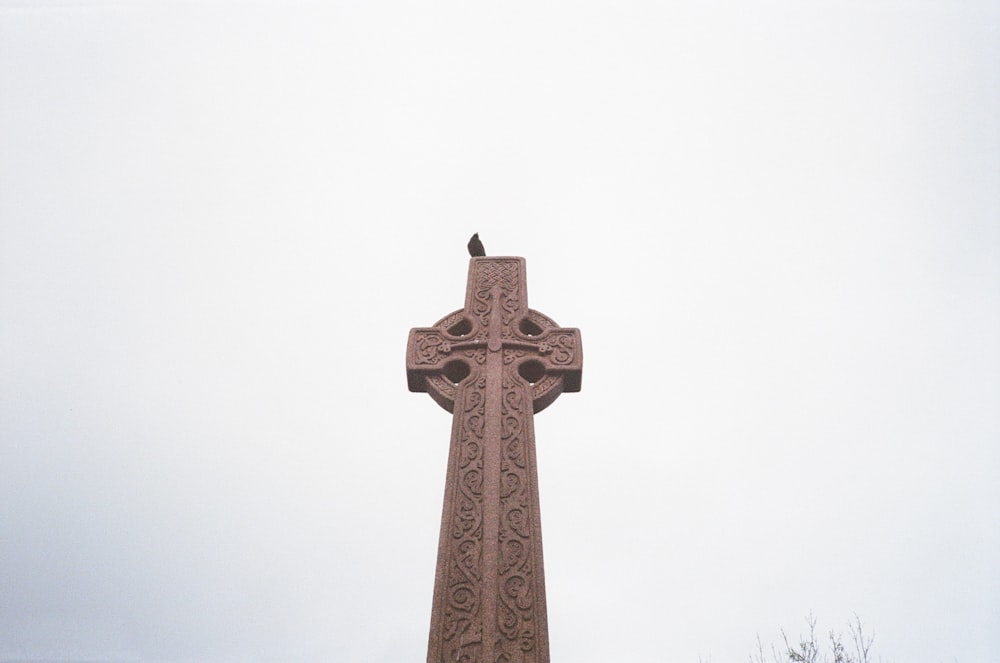 a bird sitting on a cross