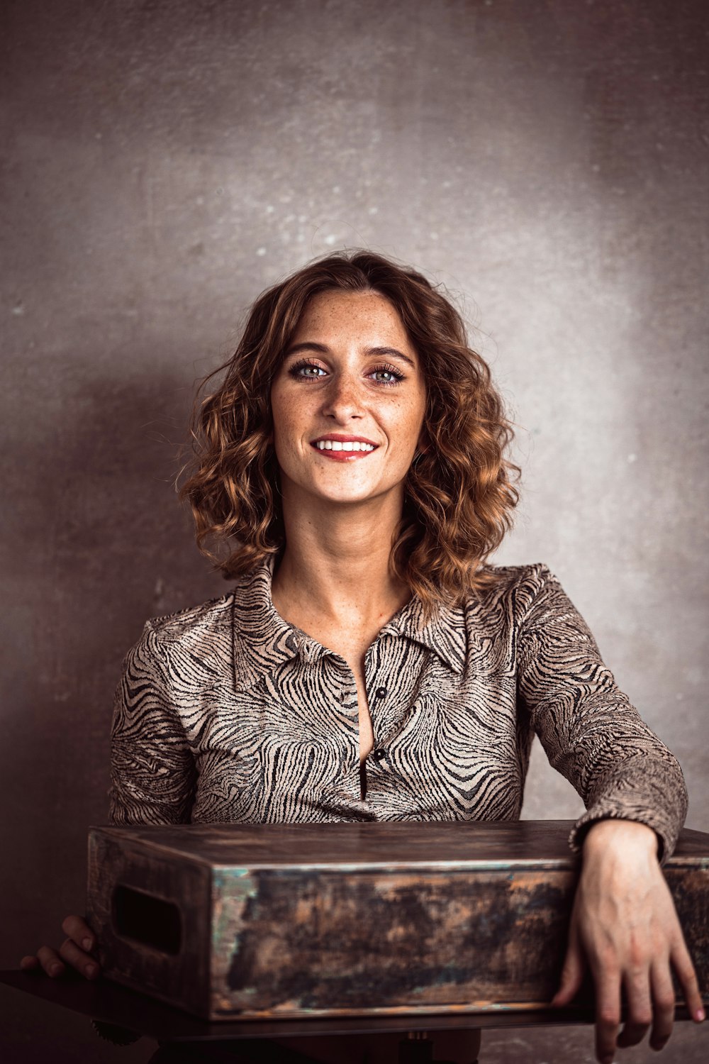 a woman smiling and holding a wooden box