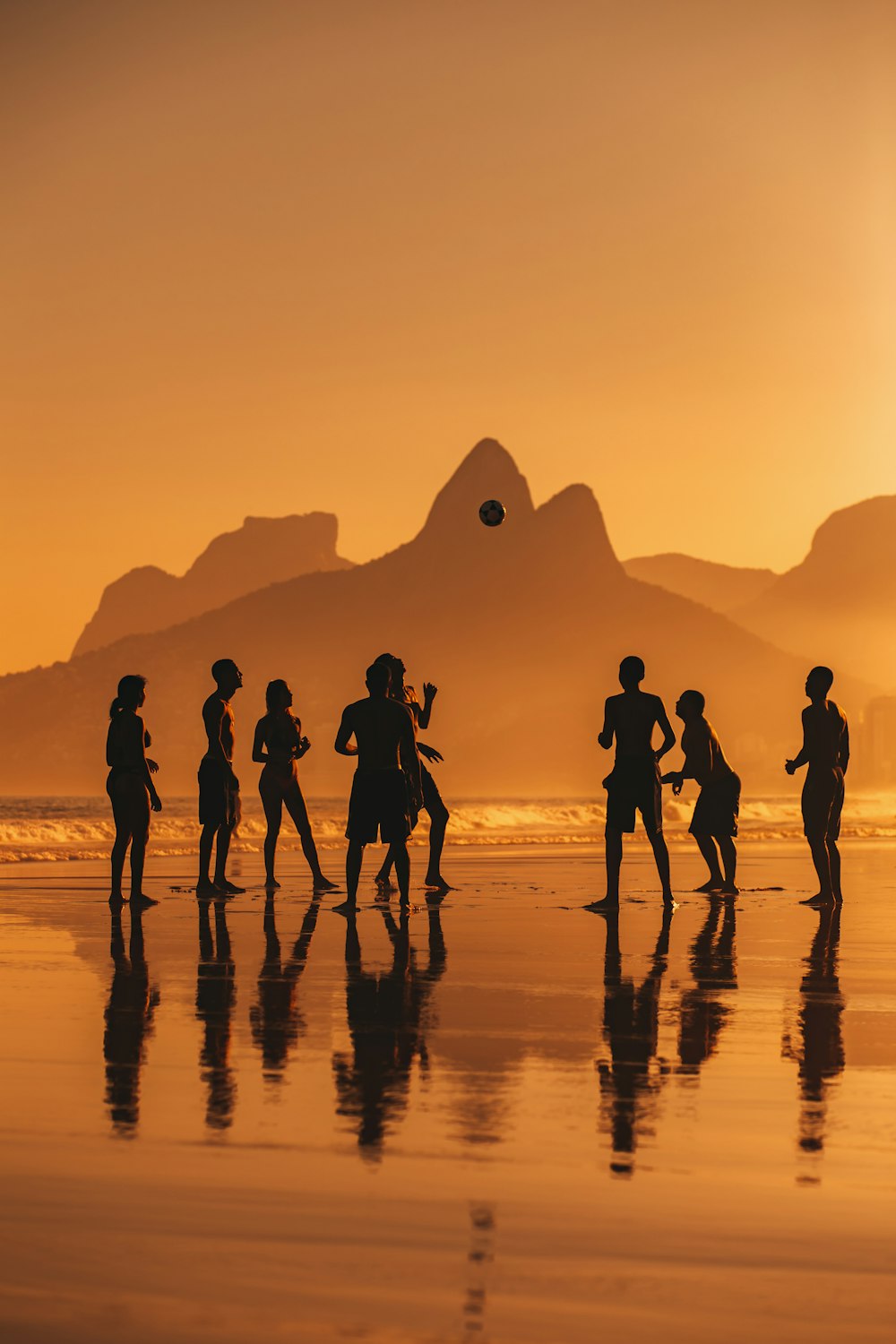 a group of people standing on a beach with a pyramid in the background
