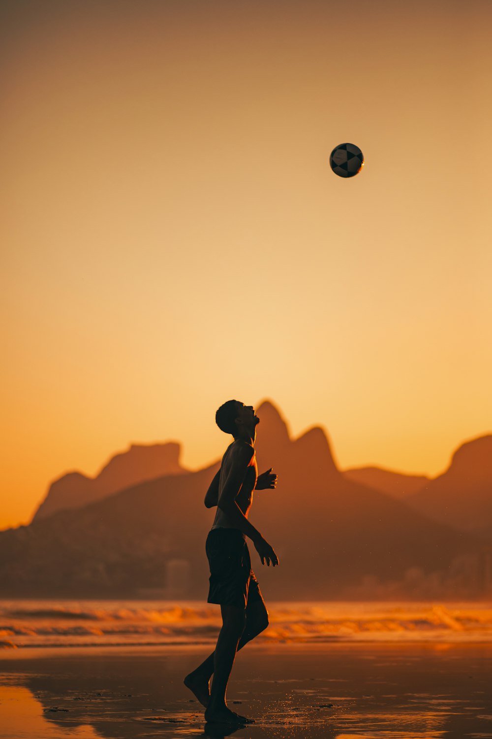 a man and woman playing with a ball on a beach