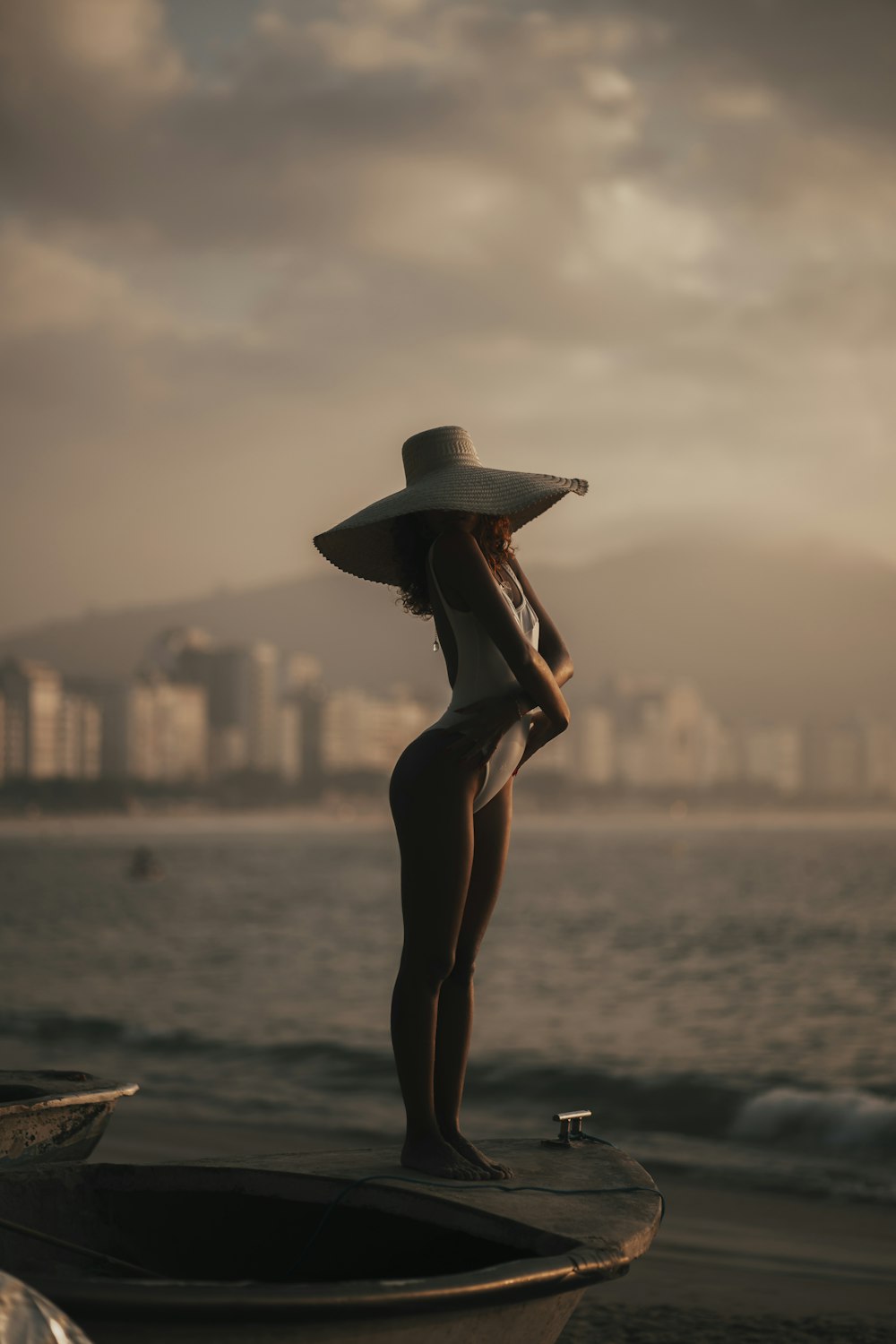 a person in a hat and dress standing on a boat in the water