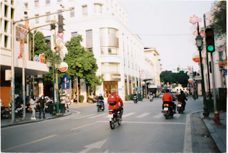 a group of people ride motorcycles down a street