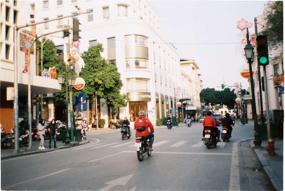 a group of people ride motorcycles down a street