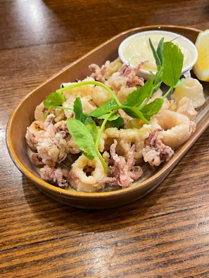 Close-up of crispy golden fried calamari with a wedge of lemon and a sprinkle of fresh parsley.