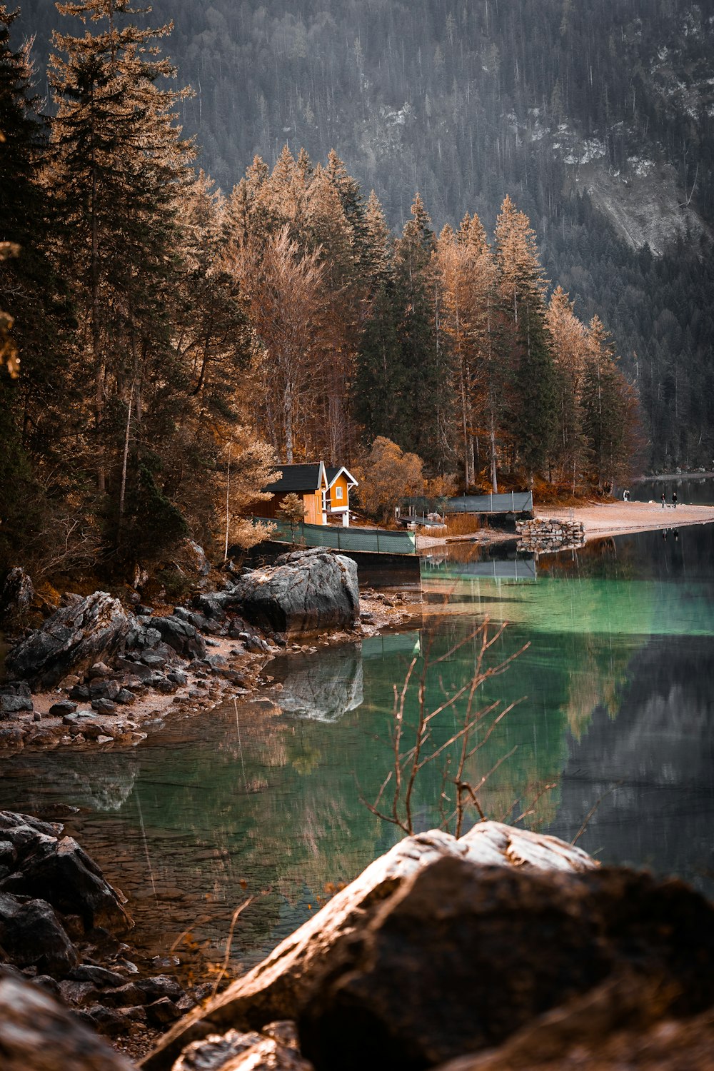 a house on a lake surrounded by trees and mountains