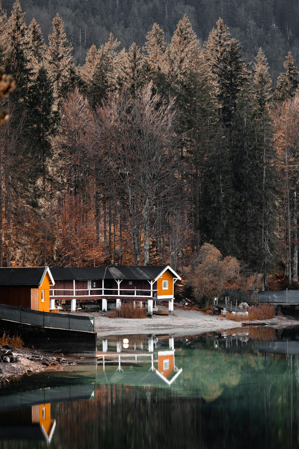 a house on a dock by a lake with trees in the background