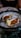 Two oysters served on a bed of ice in a decorative bowl. The oysters contain a red sauce and a slice of cucumber.