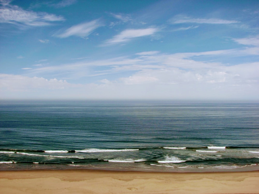 a beach with waves and blue sky