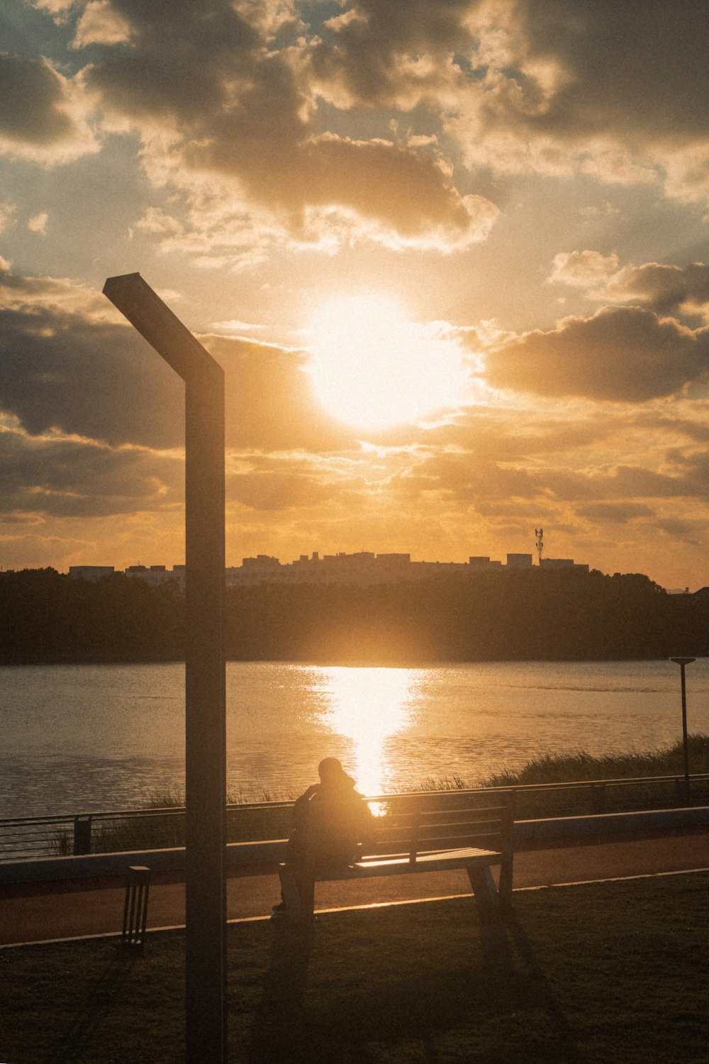 a person sitting on a bench looking at the sunset