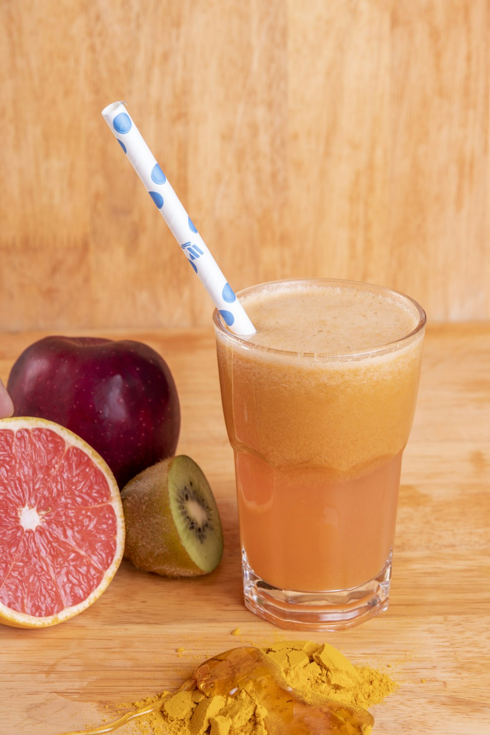 a glass of juice next to a couple of apples and a knife