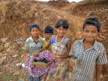 Smiling kids enjoying fresh fruit kebabs outside on a bright day surrounded by greenery.