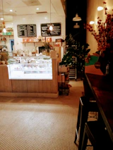An inviting display of pastries and coffee cups arranged neatly on a maroon countertop with green plants nearby.