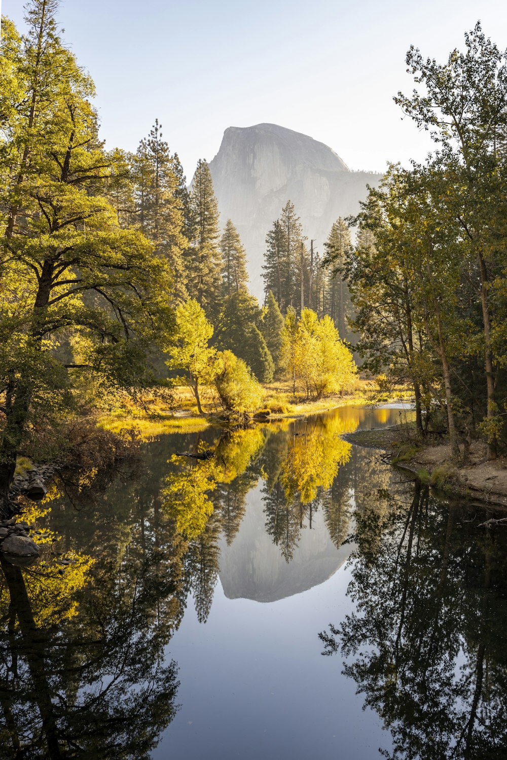 a body of water with trees around it and mountains in the background