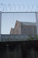 Exterior view of a secure federal prison building with perimeter fencing.