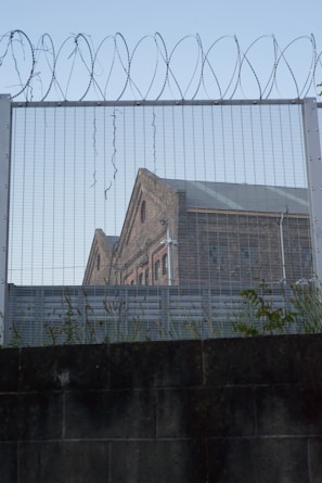Exterior view of a secure federal prison building with perimeter fencing.