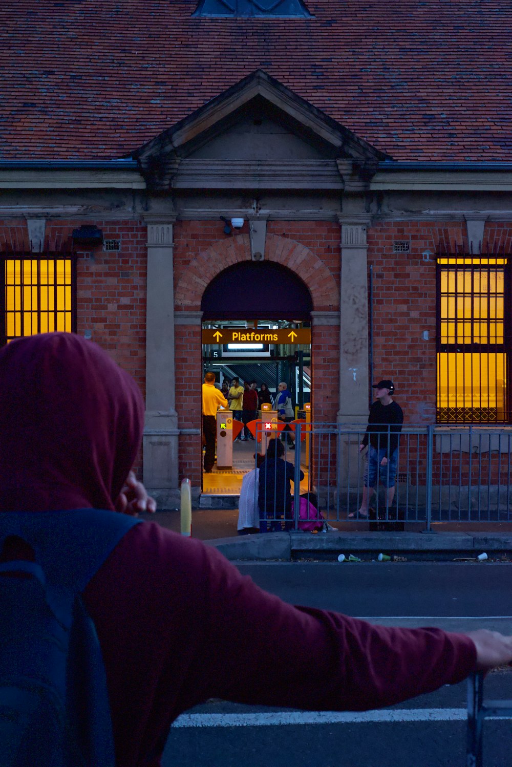 a person's leg in front of a brick building with people walking