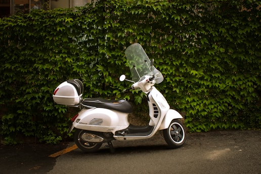 a white motorbike parked on the side of a road