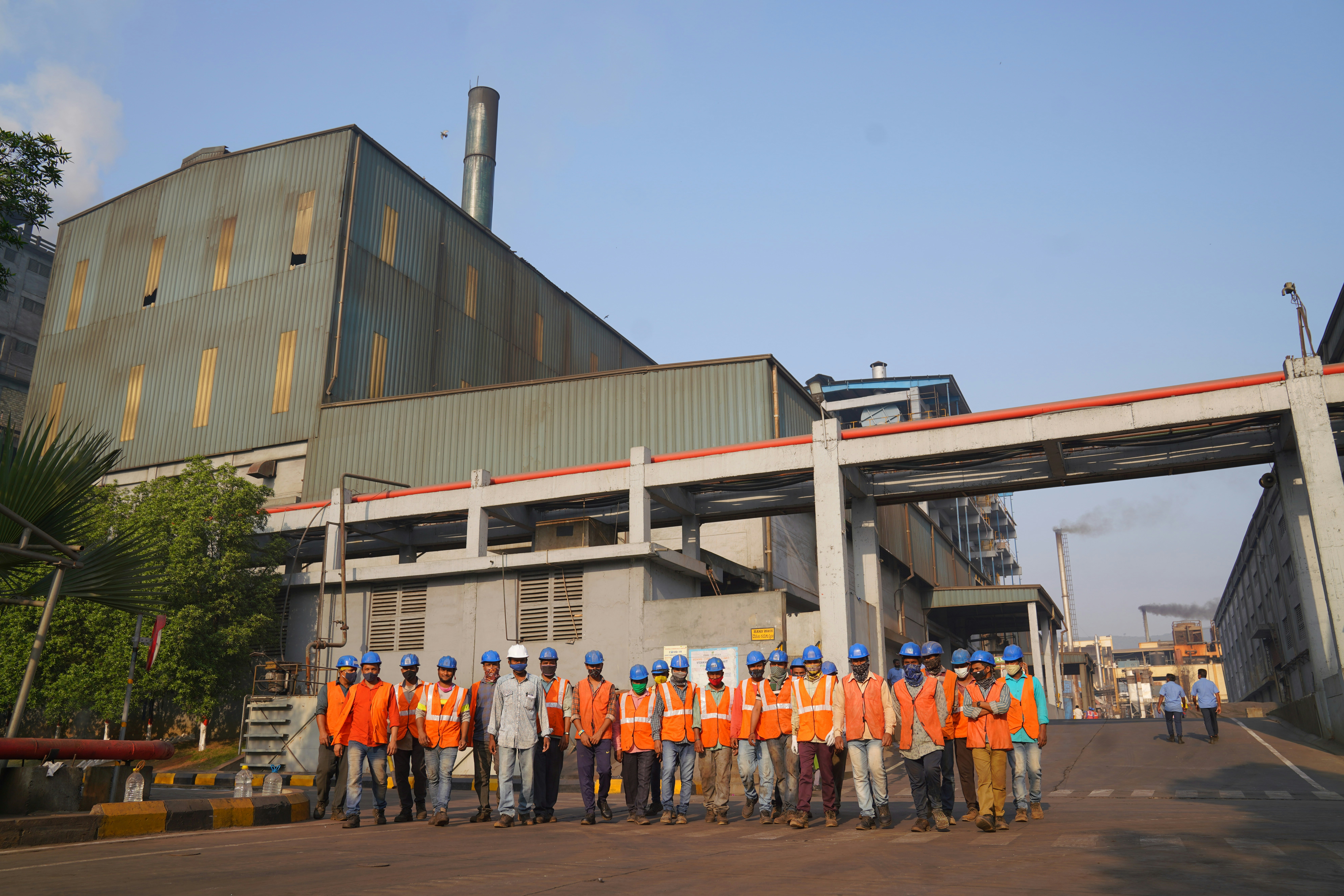 a group of people in orange vests standing in front of a building