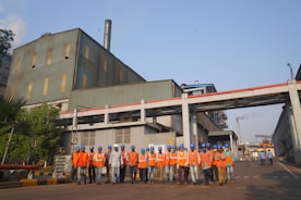 a group of people in orange vests standing in front of a building