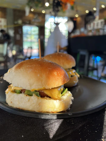 Close-up of gourmet sliders with melted cheese and fresh greens, served on a sleek black slate.