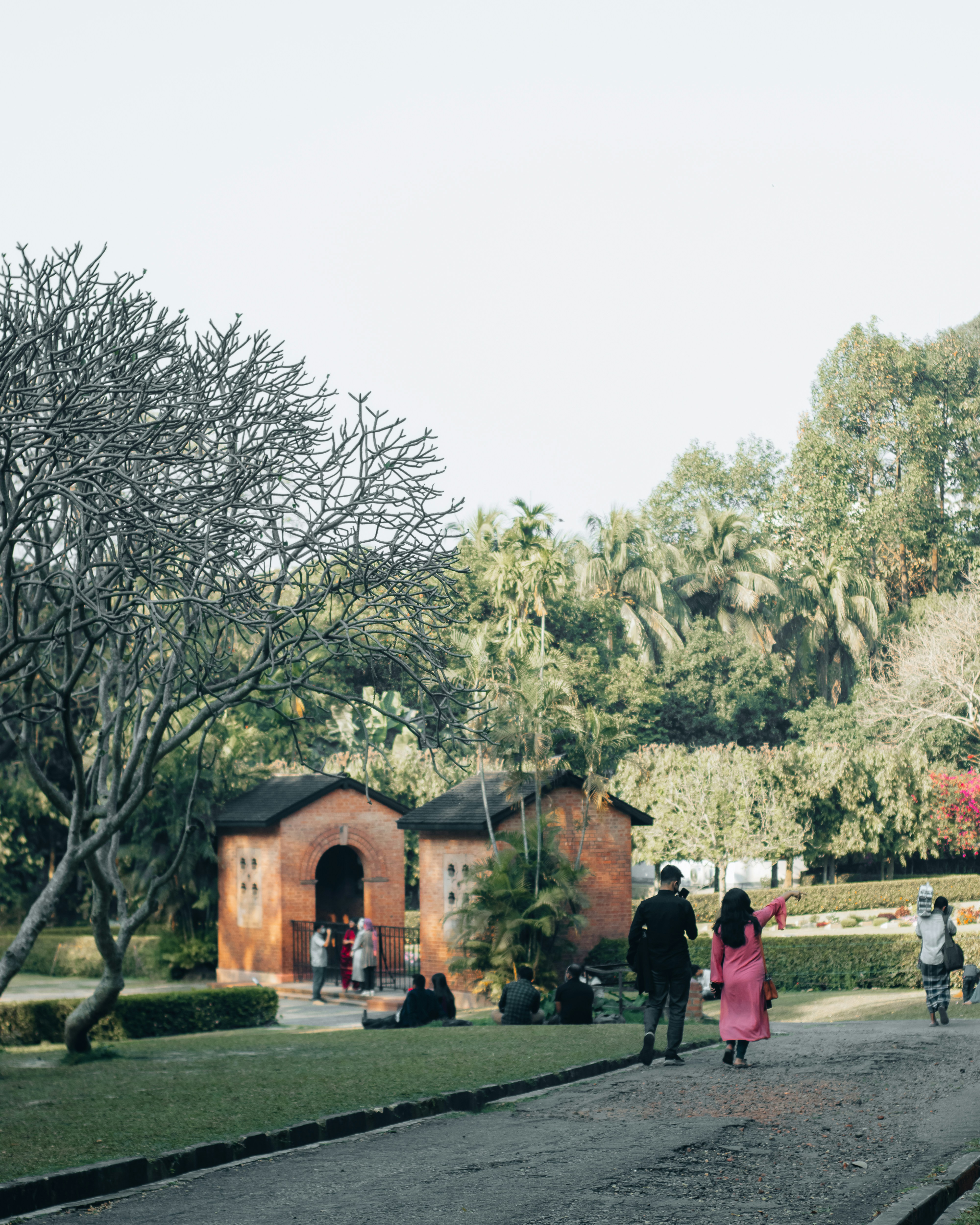 a group of people walking outside of a building with trees in the back