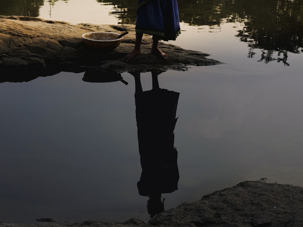 a person standing in a body of water with a person's foot on a rock in the